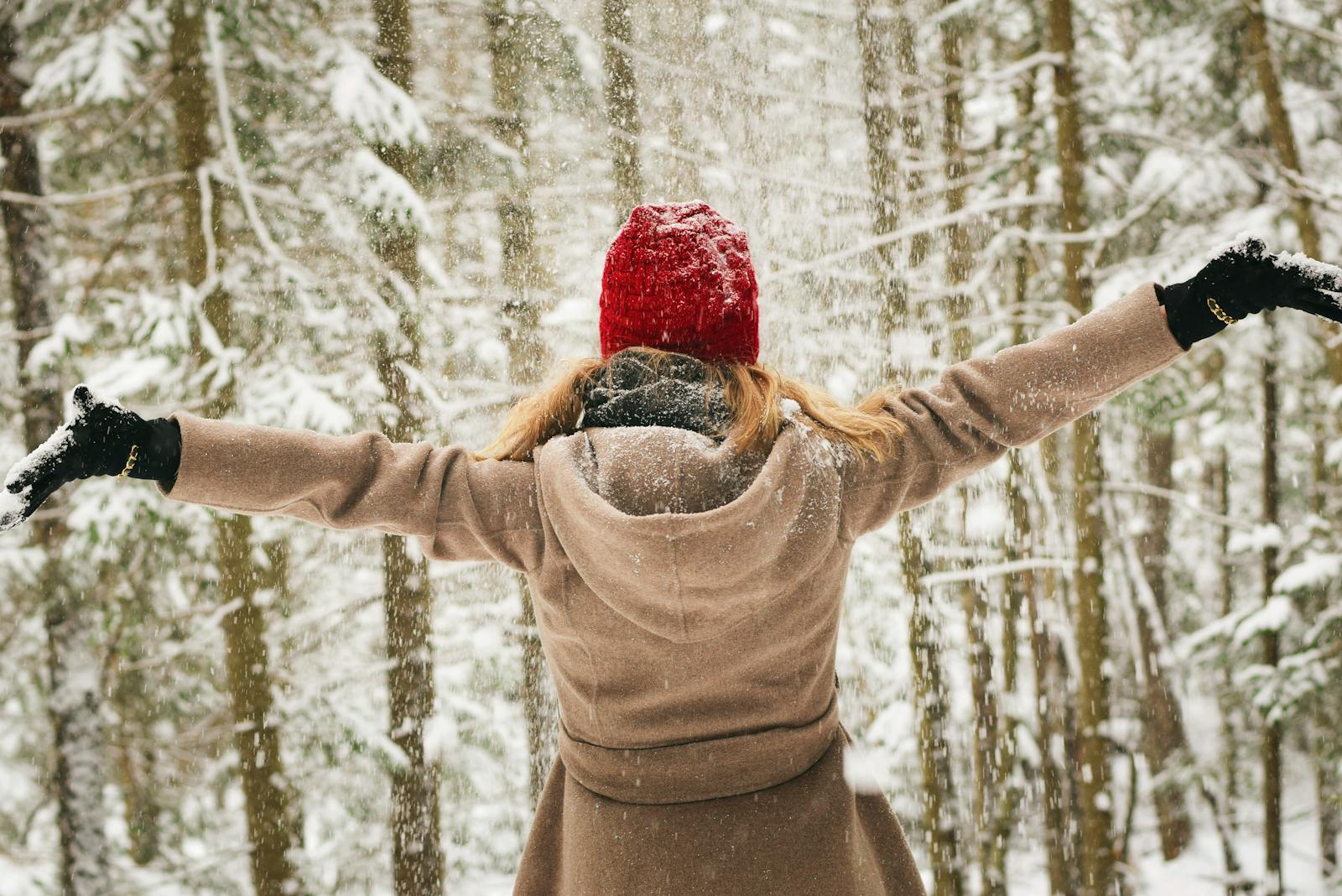 Woman in red hat enjoying a snowy winter day in Lake Placid forest.